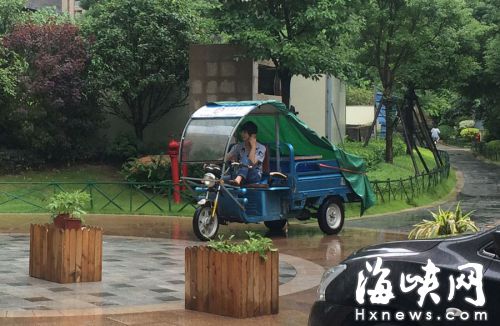 這名快遞哥騎行在小區(qū)通道內(nèi)，一邊接打手機(jī)，一邊還把腳架在車前欄桿上